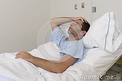 Young patient man lying at hospital bed resting tired looking sad and depressed worried Stock Photo