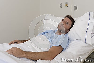 Young patient man lying at hospital bed resting tired looking sad and depressed worried Stock Photo