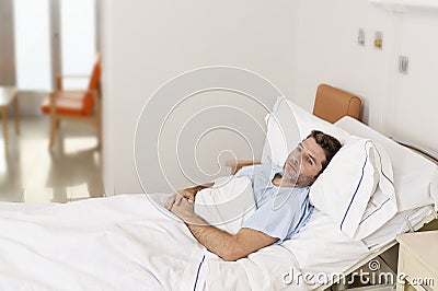 Young patient man lying at hospital bed resting tired looking sad and depressed worried Stock Photo