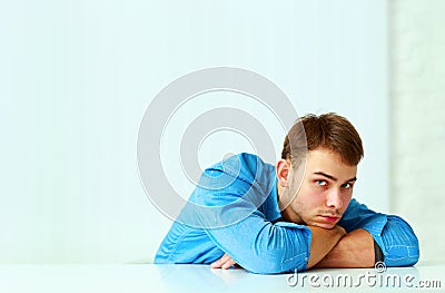 Young pensive businessman laying on the table and looking Stock Photo