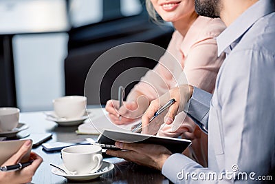 Young people drinking coffee and writing in notebooks at business meeting, business lunch concept Stock Photo