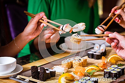 Young people eating sushi in restaurant Stock Photo