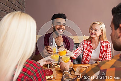 Young People Group Man And Woman Sitting In Burger Cafe, Toasting Orange Juice Order Fast Food On Wooden Table Stock Photo