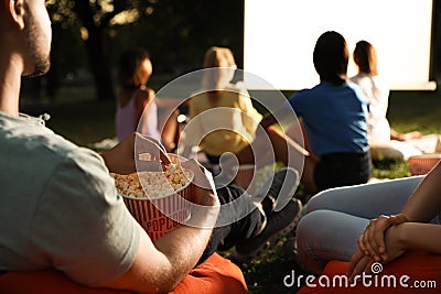 Young people with popcorn watching movie in open air cinema. Space for text Stock Photo