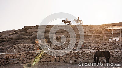 Young people riding horses doing excursion at farm ranch in sunset time Stock Photo