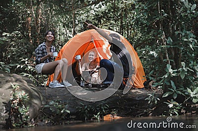 Young People Trekking Group Sitting Relaxed in the Rainforest Near a Natural Stream. Looking at Natural Views in the Forest while Stock Photo