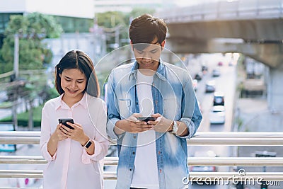 Young people are using smartphone and smiling while sitting on free time. technology concept. Stock Photo