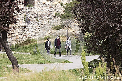 Young people wearing face masks while walking in nature, in city public park Editorial Stock Photo