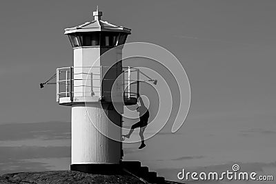Young person hanging from a lighthouse Stock Photo