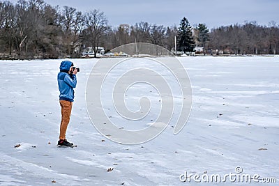 Young Photographer Taking Pictures on Snowy Lake Stock Photo