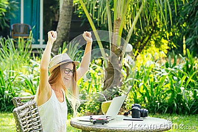 Young photographer woman feeling happy becouse she get money online while sitting at tropical cafe Stock Photo