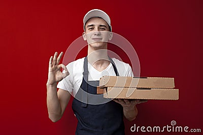 Young pizza delivery man holds boxes and shows okay hand, express delivery service Stock Photo