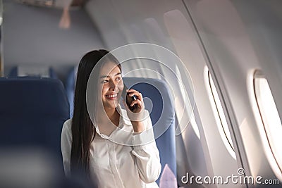 Young plane passenger business woman using smartphone communicate, businesswoman working while flying at plane Stock Photo