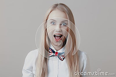 Young playful cute blonde with bow tie opens her mouth in surprise Stock Photo