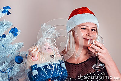 Young pleasant happy woman with glass of champagne in hand and pig toy gift Stock Photo