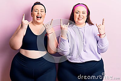 Young plus size twins wearing sportswear shouting with crazy expression doing rock symbol with hands up Stock Photo