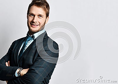 Young positive handsome man in official costume and tie standing and smiling over light grey wall background Stock Photo