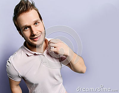 Young positive handsome man in white t-shirt standing and feeling happy over light grey wall background Stock Photo