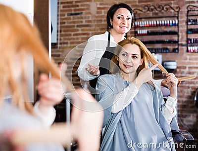 Woman points to master in hairdress salon right hair length for haircut Stock Photo