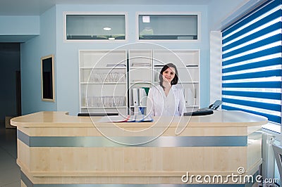 Young practitioner doctor working at the clinic reception desk, she is answering phone calls and scheduling appointments Stock Photo