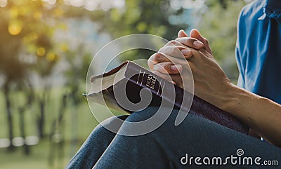 Young prayer sitting outdoor for reading bible and worship god, garden nature background. Bible concept Stock Photo