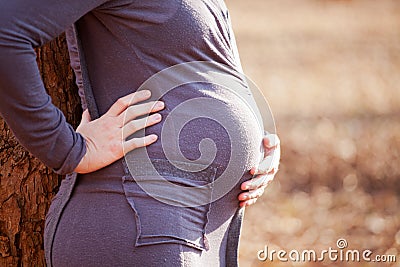 Young pregnant Caucasian woman holding her back and belly Stock Photo