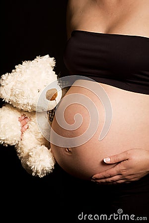 Young pregnant Caucasian woman holding teddy bear Stock Photo