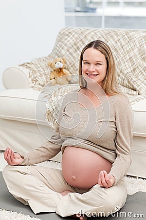 Young pregnant woman doing yoga on the floor Stock Photo