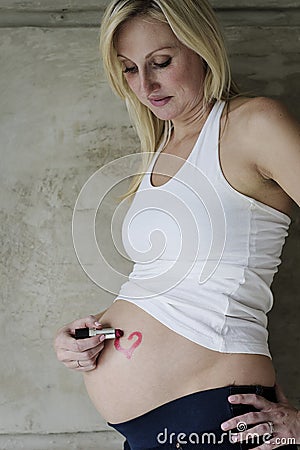 Young pregnant woman drawing a lipstick heart on belly Stock Photo