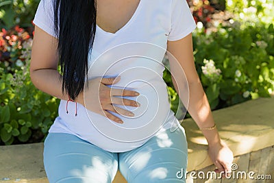 A young pregnant woman holds her hands on her tummy and feels the tremors of her baby Stock Photo