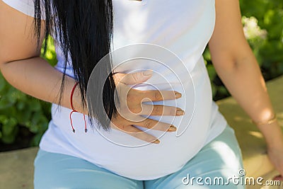 A young pregnant woman holds her hands on her tummy and feels the tremors of her baby Stock Photo