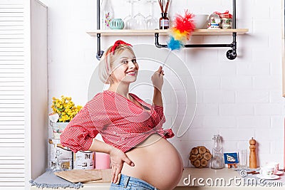Young pregnant woman iinduces cleanliness in the kitchen with pipidaster Stock Photo