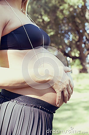 Young pregnant woman at park touching her belly Stock Photo