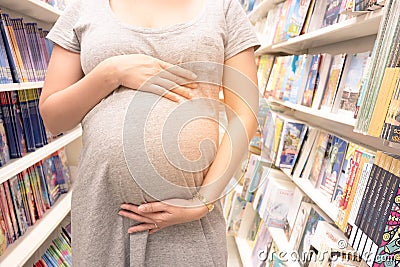 Young pregnant woman touching her belly in bookstore. Editorial Stock Photo