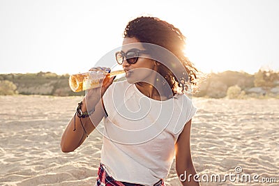 Young pretty african girl in sunglasses drinking beer Stock Photo