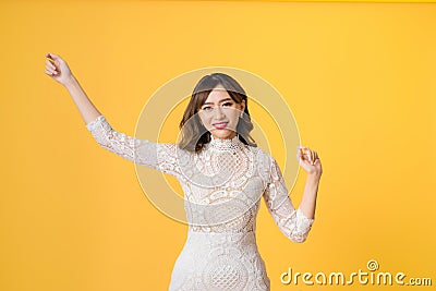 Young pretty Asian woman smiling with energetic movement studio shot isolatede on colorful yellow background Stock Photo