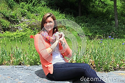 Young pretty brunette sitting on rock in garden Stock Photo