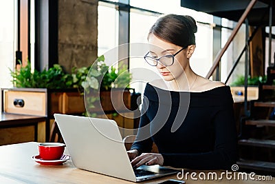 Young pretty business woman works on a laptop, uses a smartphone, a freelancer, a computer, financial analyst, a sales manager, pr Stock Photo