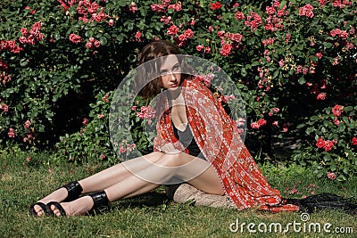 Young pretty fashion model sits in the rose garden. Outdoor portrait of a romantic girl with hard sunlight Stock Photo