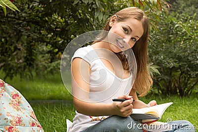 Young pretty female student with books working in a park Stock Photo