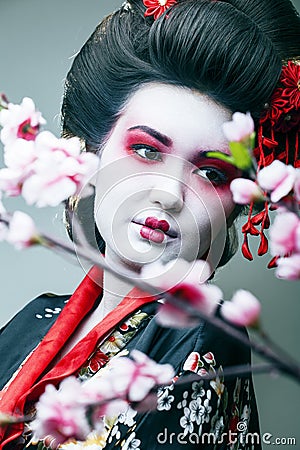 Young pretty geisha in black kimono among sakura, asian ethno closeup Stock Photo