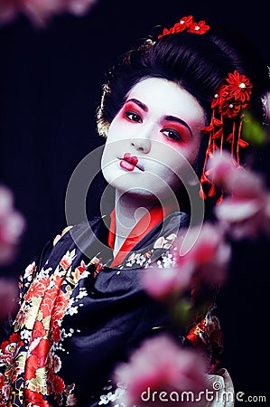 young pretty geisha in kimono with sakura and decoration on blac Stock Photo