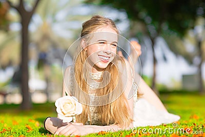 A young pretty girl holding a white rose in a sunny park. Stock Photo