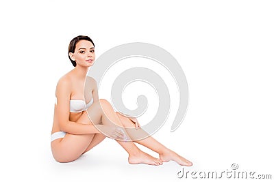 Young pretty girl in lingerie shaving her legs with razor isolated on white clean clear background. Body care waxing shaving hair Stock Photo