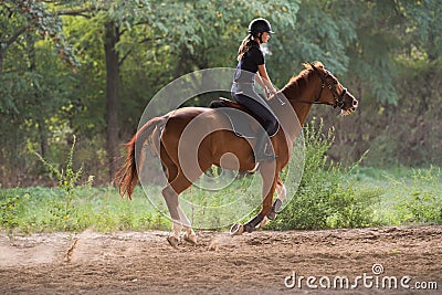 Young pretty girl riding a horse with backlit leaves behind Stock Photo