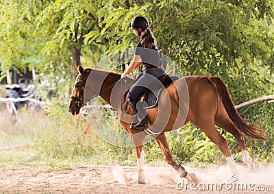 Young pretty girl riding a horse with backlit leaves behind Stock Photo