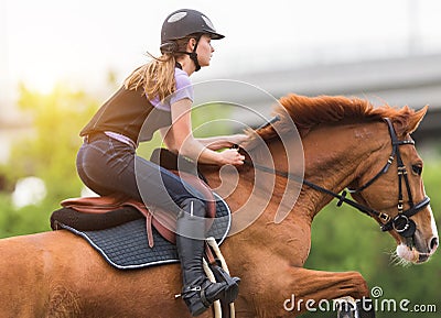 Young pretty girl riding a horse with backlit leaves behind in s Stock Photo