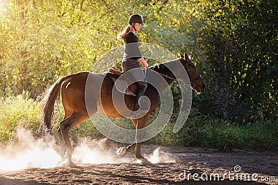 Young pretty girl - riding a horse with backlit leaves behind Stock Photo