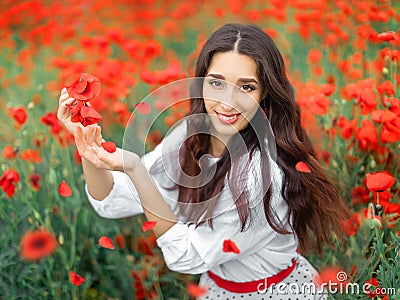 Young pretty girl Slavic or Ukrainian posing in folk dress on a flowering poppy field. Female holding poppy flowers with Stock Photo