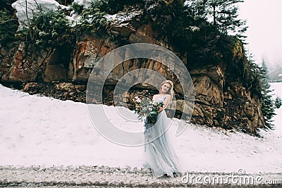 The young pretty girl waits for her lover in the middle of the mountains covered with snow Stock Photo